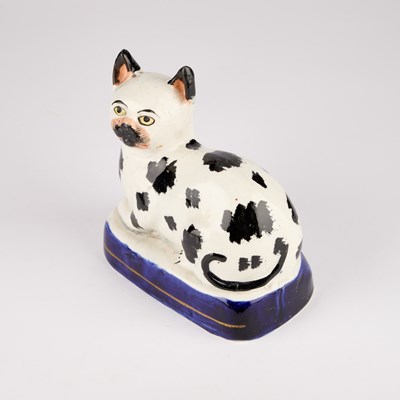 Lot 35 - A VICTORIAN STAFFORDSHIRE POTTERY MODEL OF A RECUMBENT CAT, CIRCA 1850
