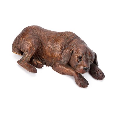 Lot 1017 - A BLACK FOREST LINDEN WOOD CARVING OF A RECUMBENT DOG