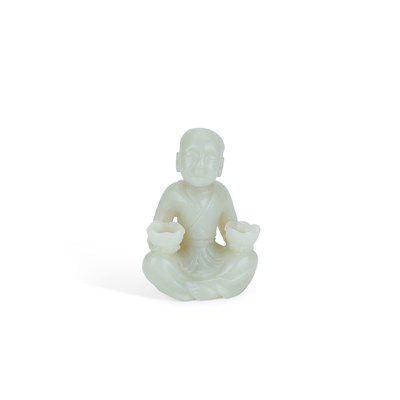 Lot 565 - A CHINESE PALE CELADON JADE CARVING OF A SEATED BOY