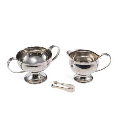 Lot 314 - GUILD OF HANDICRAFT: A GEORGE V ARTS AND CRAFTS CREAM JUG, SUGAR BOWL AND SUGAR TONGS